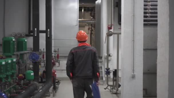 Ένας νεαρός μηχανικός είναι σε ένα τεχνικό δωμάτιο. στο εργοστάσιο — Αρχείο Βίντεο