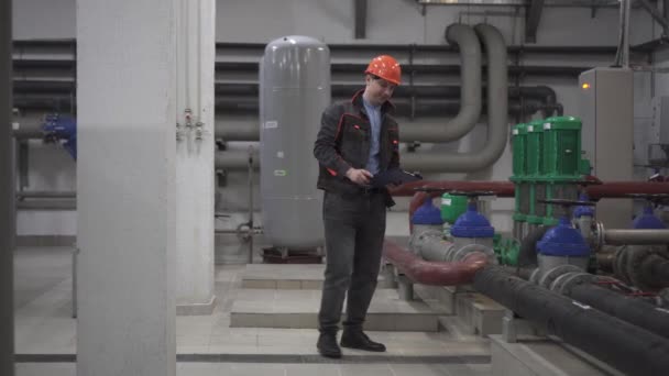 Ένας νεαρός μηχανικός είναι σε ένα τεχνικό δωμάτιο. στο εργοστάσιο — Αρχείο Βίντεο