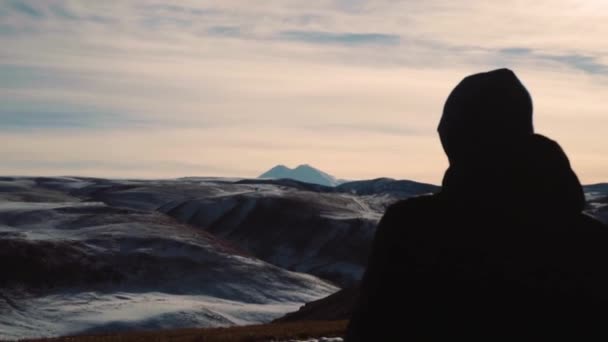 El tipo está de pie sobre un fondo de montañas — Vídeo de stock