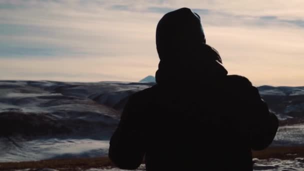 Хлопець стоїть на тлі гір — стокове відео