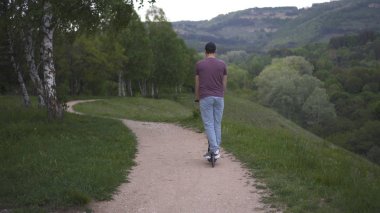 Parkta elektrikli scooter kullanan bir adam.