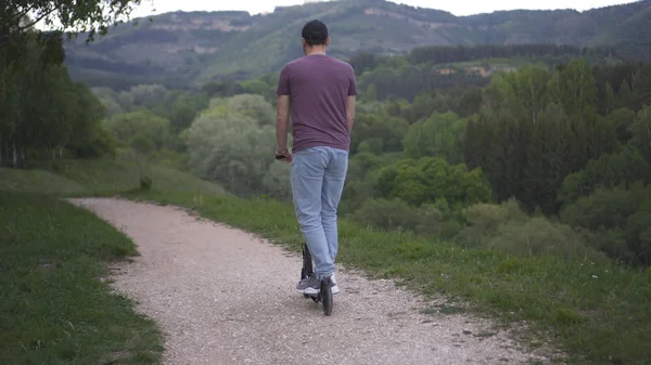 Parkta elektrikli scooter kullanan bir adam.