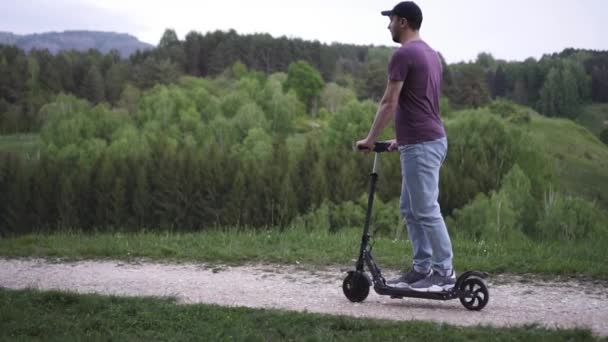 Hombre montando un scooter eléctrico en el parque — Vídeos de Stock