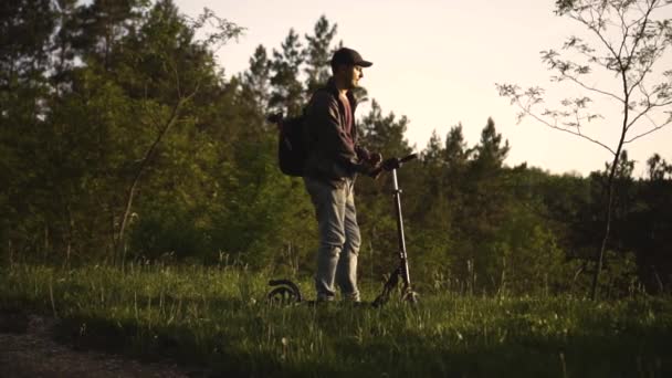 Uomo a cavallo di uno scooter elettrico nel parco — Video Stock