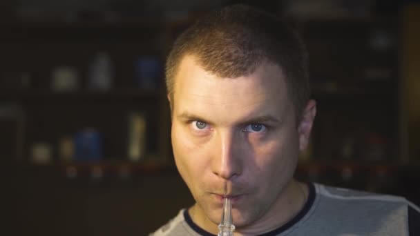 Der Typ raucht eine Wasserpfeife und atmet Rauch in die Kamera aus — Stockvideo