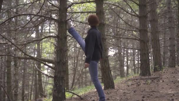 Девушка, делающая растяжки в диком лесу — стоковое видео