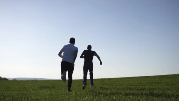 Két fiatal férfi fut át a pályán — Stock videók
