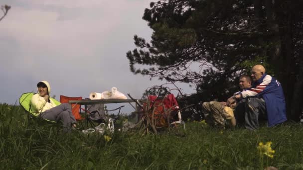 Люди отдыхают на природе вокруг костра на закате — стоковое видео