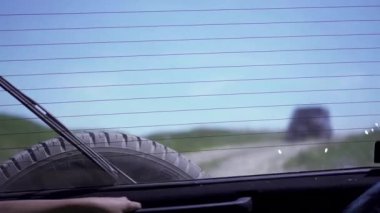 Genç bir kız bir SUV için bir tozlu yolda bagajda alınır