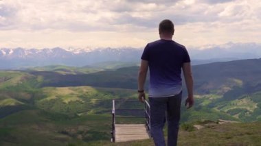 adam dağlara ve ormana bakan köprüye gider.