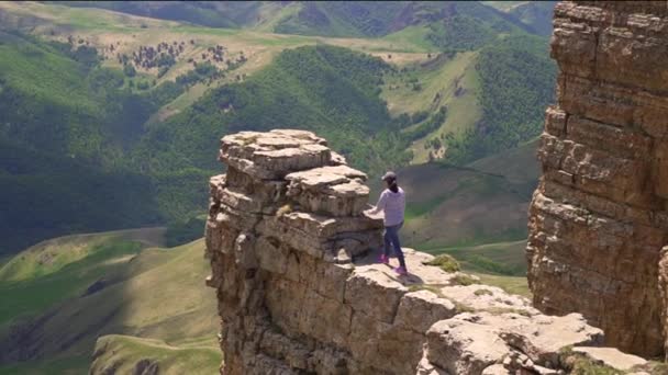 Дівчина йде на край скелі і відкриває руки — стокове відео