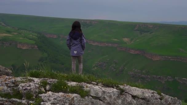 Fiatal ázsiai lány áll a szélén egy szikla, kilátással a hegyekre és az erdőben — Stock videók