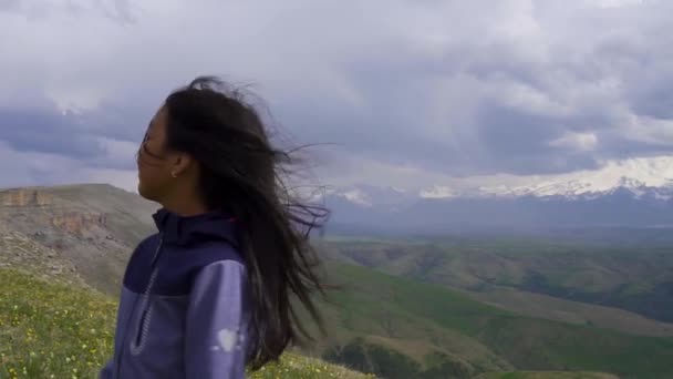 Pequeña chica asiática girando en el viento sobre un fondo de montañas — Vídeo de stock