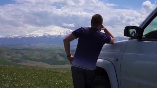 Tipo se para cerca de la camioneta con una vista de las montañas y el bosque — Vídeos de Stock