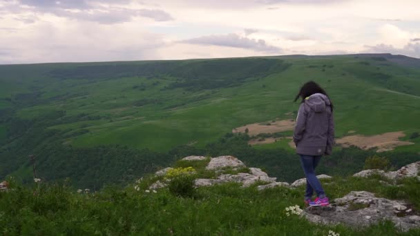 Ragazza va al bordo di una scogliera e apre le braccia — Video Stock