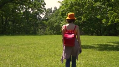 turuncu şapkalı kız yeşil parkta yürür, gün