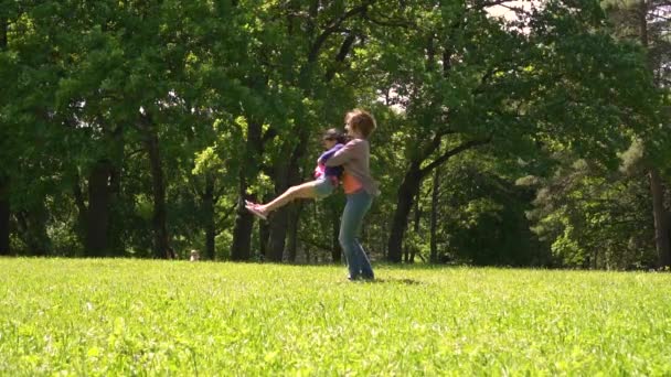 Mamá está rodeando a una niña en un parque, una familia multirracial, día — Vídeos de Stock