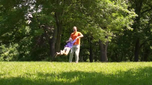 Papá está rodeando a una niña en un parque, una familia multirracial, día — Vídeo de stock