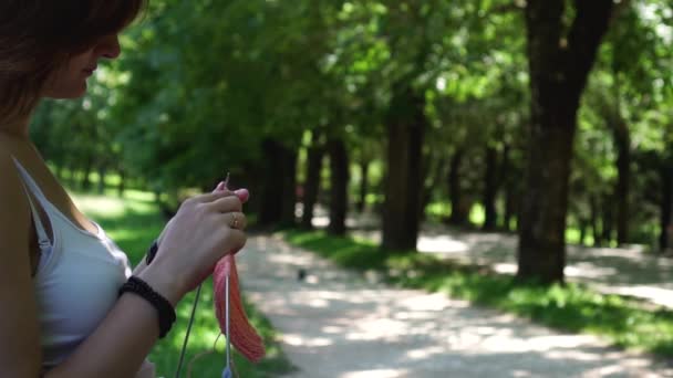 Jeune fille faire du tricot dans le parc sur le banc — Video