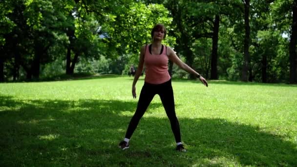 Flicka gör fitness i parken på gräset — Stockvideo