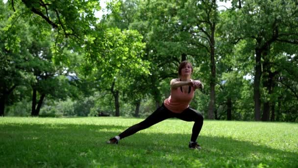 Chica haciendo sentadillas en el parque en la hierba — Vídeos de Stock