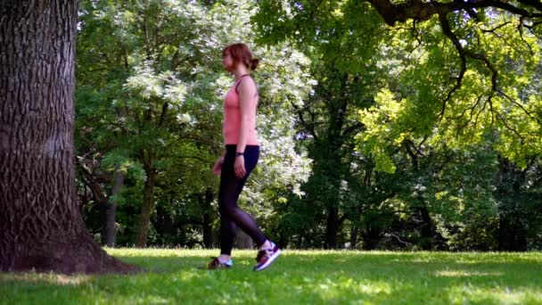 Flicka som gör garn av trädet på gräset i parken — Stockvideo