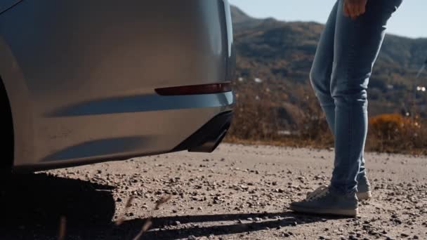 Дівчина відкриває автомобільний багажник з жестом ніг — стокове відео