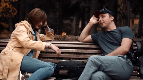 Chico y chica están sentados en el parque y hablando — Vídeos de Stock