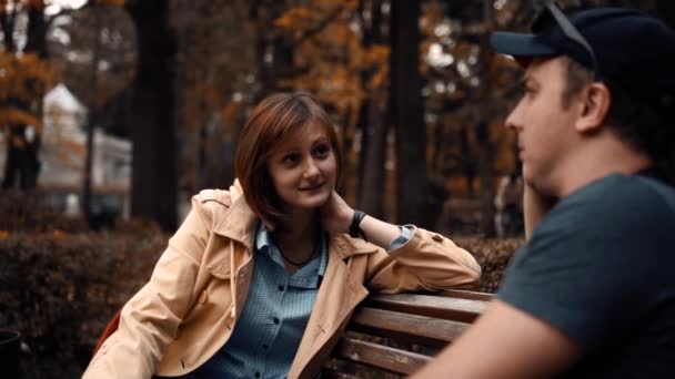 Chłopak i dziewczyna siedzą w parku i rozmawiają — Wideo stockowe