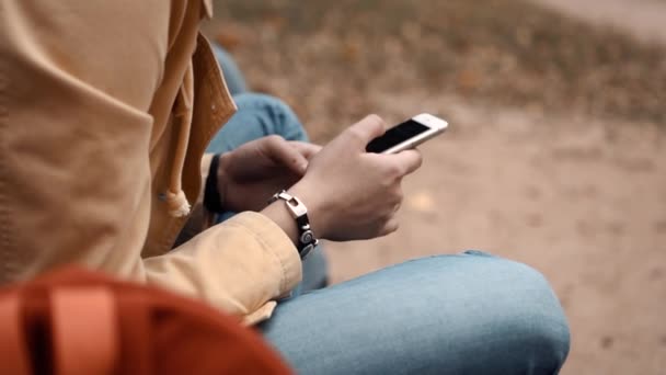 携帯電話を持って公園に一人で座っている若い女の子は — ストック動画