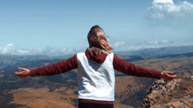 Kız ellerini dağların arka planına koydu.