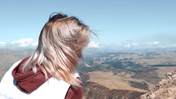 Meisjes haar fladderen in de wind tegen de achtergrond van de bergen — Stockvideo