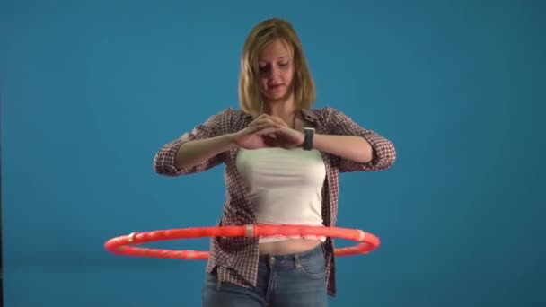 Meisje draait een hoepel op een blauwe achtergrond slow mo — Stockvideo