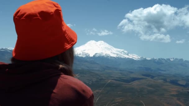 Chica sentada sobre un fondo de montañas — Vídeo de stock