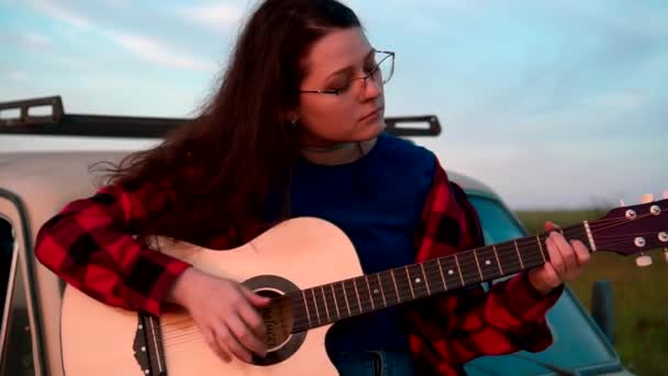 Dziewczyna gra na gitarze o zachodzie słońca — Wideo stockowe