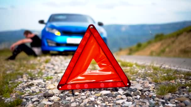 Il ragazzo ha messo un segnale di arresto di emergenza e si siede vicino alla macchina rotta — Video Stock