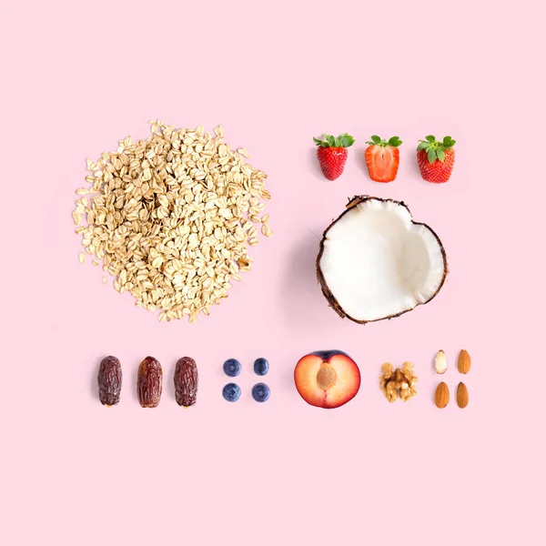 Creative layout made of oatmeal, coconut, strawberry, plum, dried dates, blueberry, almond and walnut. Flat lay. Food concept.