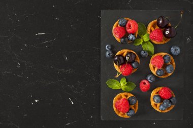 Belçika Waffle böğürtlen, ahududu, kiraz ve taze nane bir siyah mermer tablo. Üstten görünüm.