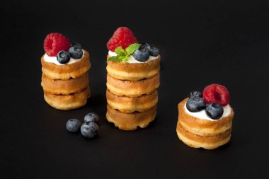 Yaban mersini, ahududu ve siyah arka plan üzerine taze nane ile Belçika waffle yığını. Makro fotoğraf, portre.