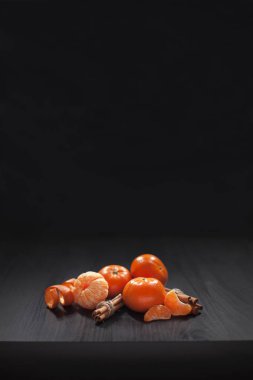 Noel kompozisyon. Mandalina, mandalina dilimleri, mandalina kabuğu ve siyah arka plan üzerine tarçın. Noel, kış, yeni yıl, Cadılar Bayramı kavramı. Kopya alanı.