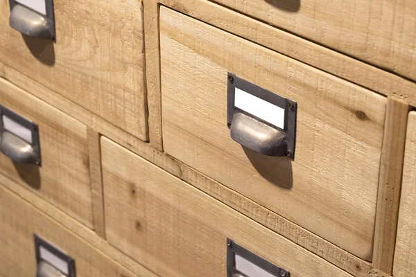 Modern wooden drawers (boxes) filing cabinet with blank mockup metal file labels (tags) with copy space