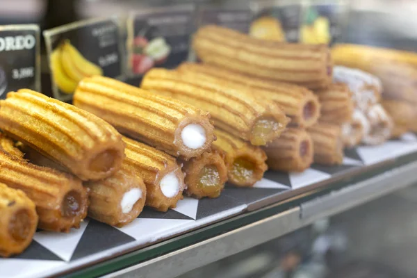 Verschillende soorten van traditionele zoete Spaanse dessert churros met het invullen van de markt of bakkerij showcase. Warm gebakken gebak schotel. — Stockfoto