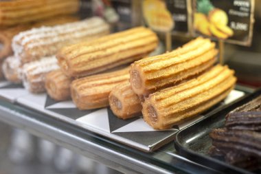 Pazar veya fırın vitrin doldurma ile geleneksel tatlı İspanyol tatlı churros farklı türleri. Sıcak pişmiş pasta çanak.