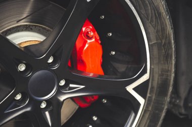 Siyah alaşımlı disklere sahip modern otomobilin kırmızı fren balataları ve diskleri.