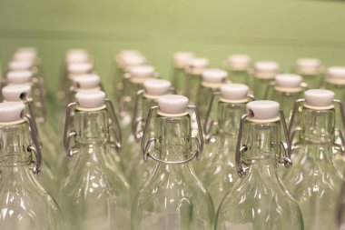 Kapaklı ve yeşil arka planlı bir sürü yeniden kullanılabilir cam şişe. Sıfır atık ve plastik konsept yok. Çevre ve ekolojinin bakımı.