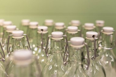 Kapaklı ve yeşil arka planlı bir sürü yeniden kullanılabilir cam şişe. Sıfır atık ve plastik konsept yok. Çevre ve ekolojinin bakımı.