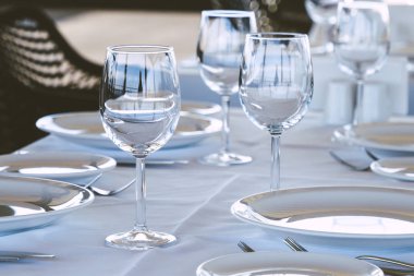 Restoranda masa ayarı. Boş şarap bardakları, tabaklar, çatallar, masa örtüsündeki bıçaklar. Zarif restoran iç.