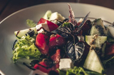 Beyaz peynir ve otlar ile popüler Yunan sebze salatası. Restoranda ahşap masada salata ile tabak. Fotoğrafı kapat.