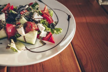 Beyaz peynir ve otlar ile popüler Yunan sebze salatası. Restoranda ahşap masada salata ile tabak. Fotoğrafı kapat.