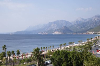 Antalya kıyılarında palmiyeler ve plajlar. Arka planda dağlar var. Türkiye 'nin en popüler tatil beldelerinden biri. 2019-08-18